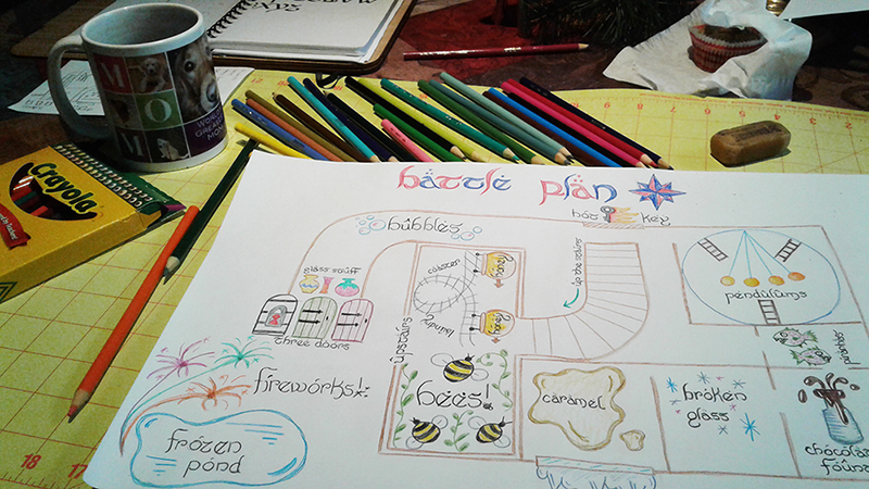A photograph of my workspace as I worked on the map, showing the map, colored pencils, and a coffee mug.